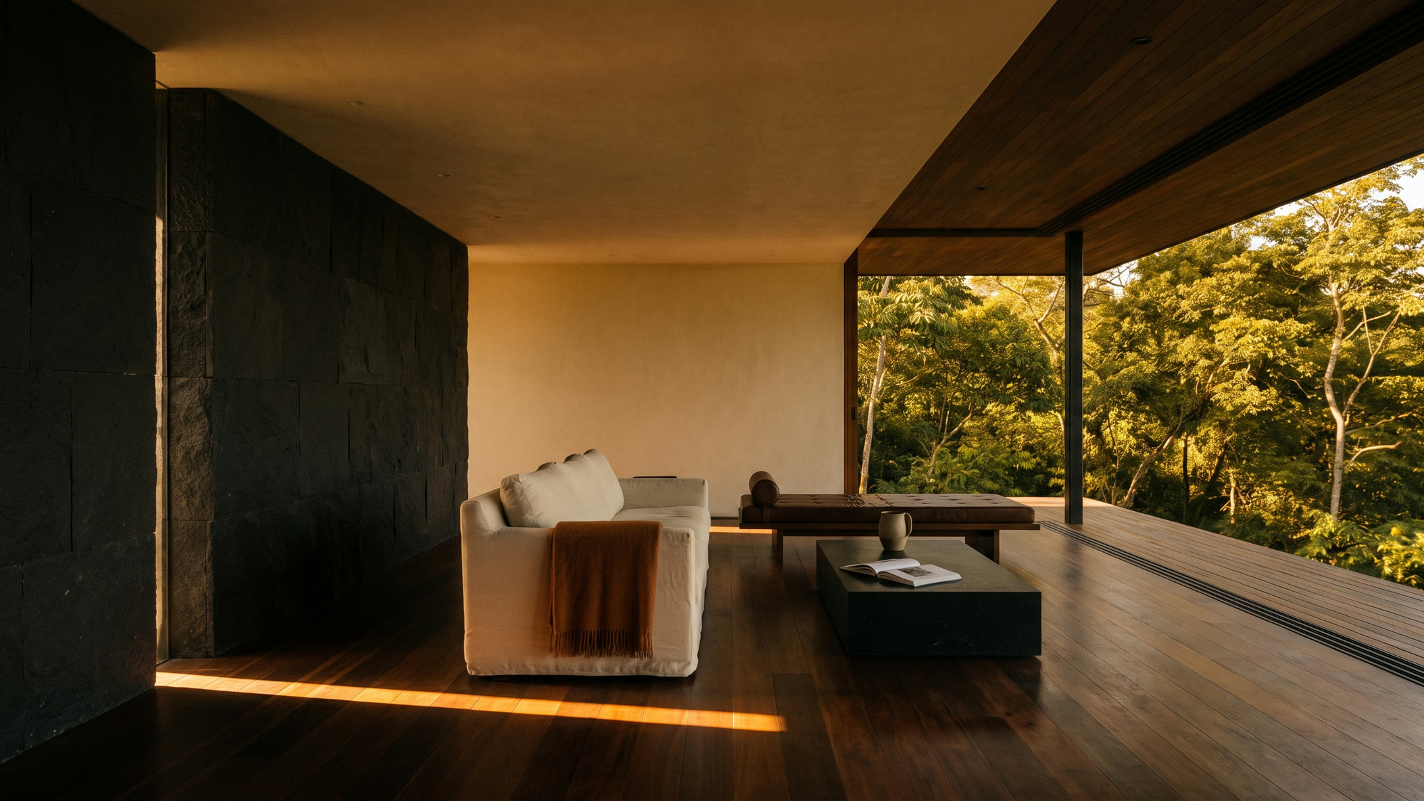 Open-sided living pavilion in late sun, one band of gold light lying across dark hardwood floorboards.